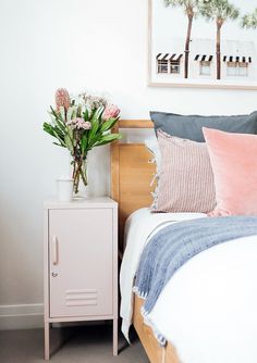 a bedroom with a bed, nightstand and flowers on the night stand in front of it