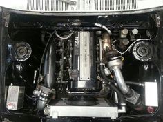 the engine compartment of an old car with its hood open and two exhaust pipes visible