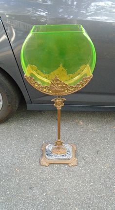 a green glass bowl sitting on top of a wooden stand next to a black car