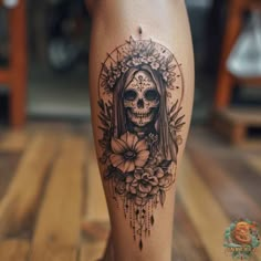 a woman's leg with a skull and flowers tattoo on the side of it