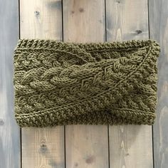 a green knitted headband laying on top of a wooden floor