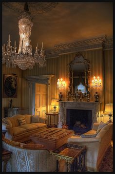 a living room filled with lots of furniture and a chandelier hanging from the ceiling