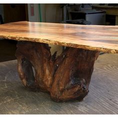 a table made out of tree trunks sitting on top of a wooden floor