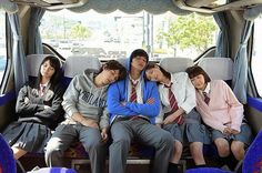 group of people sitting in the back of a bus with their arms around each other