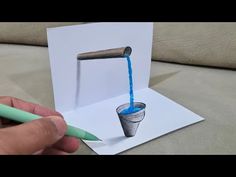 someone is drawing a card with a blue liquid pouring out of a cup on it