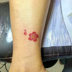 a small red flower on the ankle is shown in this tattoo photo taken by a woman