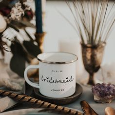 a white coffee mug sitting on top of a table next to shells and other items