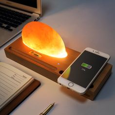 a cell phone is sitting on top of a wooden stand with an illuminated lamp next to it