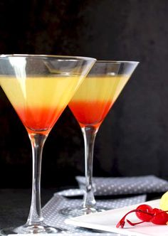 two glasses filled with liquid sitting on top of a white plate next to a slice of pineapple