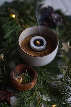 a candle that is sitting in a bowl on a table next to some christmas decorations