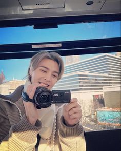 a young man taking a selfie in front of a window while holding a camera