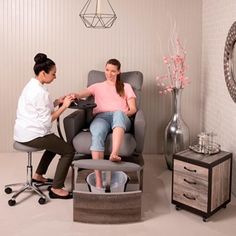 a woman sitting in a chair with another woman standing next to her