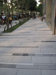 a man sitting on a bench in the middle of a sidewalk