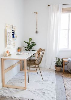 a room with a desk, chair and potted plant