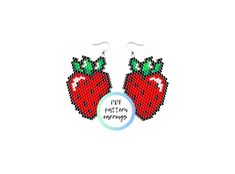 two red strawberrys with green leaves on them are hanging from the back of a pair of earrings