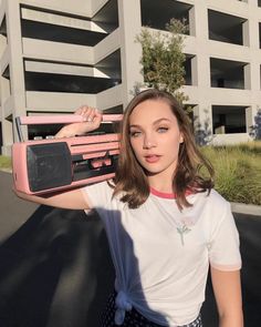 a woman holding a pink radio in front of an apartment building