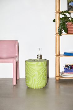 two pink chairs and a green table in a room with bookshelves on the wall