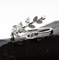 This is a very unique ring in 925 Silver Adjustable Ring with zirconia accents.  It is a vine/leaf design with a thin silver band.  Rhodium plated for color and luster.    This is a great gift for yourself or someone else!  Ring can be adjusted gently to fit most fingers but is a bit larger size so best for sizes 7 and up.  The ring comes in a beautiful black & silver kraft ring box with a care card and polishing cloth inside an organza bag.  It is ready to gift if you are purchasing for someone Laurel Leaf, Laurel Leaves, Vine Leaves, Wrap Ring, Care Card, Unique Ring, Wrap Rings, Gift Ring, Adjustable Ring