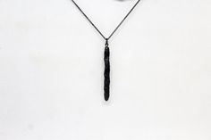 a necklace with a long black object hanging from it's side on a chain