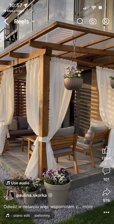 an outdoor gazebo with curtains and flowers on it