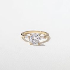 a yellow gold engagement ring with a single round diamond in the center, on a white background