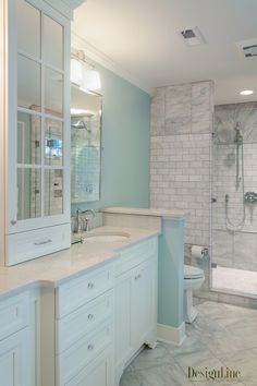 a bathroom with white cabinets and marble counter tops