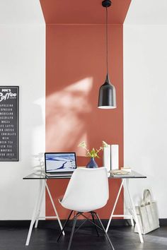 a laptop computer sitting on top of a desk next to a white chair and lamp