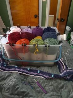 there are many yarns in the basket on the bed with it's handles