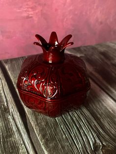 a red vase sitting on top of a wooden table