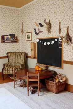 a living room filled with furniture and a chalkboard on the wall next to a wooden table