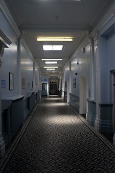 an empty hallway in a building with blue walls and white trim on the ceiling is lit by recessed lights