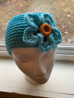 a crocheted hat with a wooden button on the side and a flower in the middle