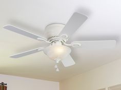 a white ceiling fan in a room with a light on the ceiling and a window behind it