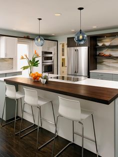 a kitchen with an island and bar stools next to the counter top in front of it