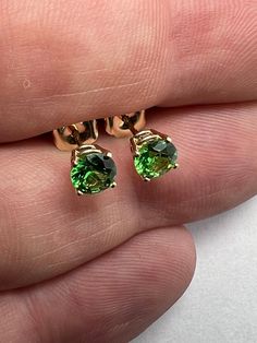 1 carat Tsavorite garnet stud earrings set in 14k yellow gold.  5mm prong set 14k yellow gold green grossular garnet earrings. 1.05 carat, round brilliant cut, 5mm tsavorite grossular green garnets from Kenya. All natural untreated, precision cut, in house, for great brilliance and color. prong set in solid 14k yellow gold. Picture of 5mm prong set next to 4mm bezel set for reference only. 1mm in gemstone size makes a large difference in appearance! See more of our earrings here .  https://www.e Green 14k Gold Jewelry With Round Stone, Fine Jewelry With Green Round Stone, Fine Jewelry Green Round Stone, Green Round Stone Fine Jewelry, Green Birthstone Jewelry With Round Cut, Fine Jewelry With Round Prong Setting, Green Solitaire Jewelry With Round Stone, Yellow Gold Tsavorite Gemstone Earrings, Green Solitaire Round Cut Jewelry