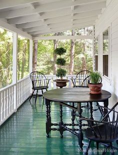 a porch with chairs and a table on the front porch, covered in white paint