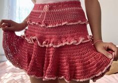 a woman wearing a red crocheted skirt with ruffles