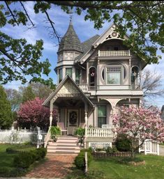 an old victorian style house with pink flowers in the front yard