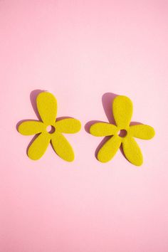 two yellow flowers on a pink surface with one flower cut out to look like the petals