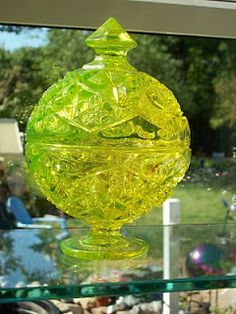 a yellow glass vase sitting on top of a glass shelf