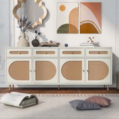 a white sideboard with wicker doors and mirrors on the wall next to it