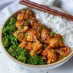 a bowl filled with rice, broccoli and chicken next to chopsticks