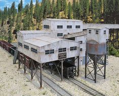 an old train station with two water tanks on the tracks and trees in the background