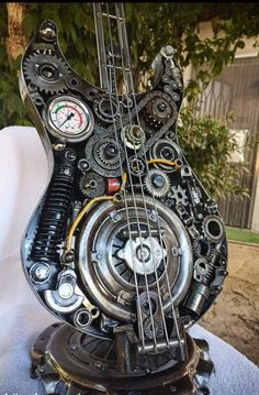 an electric bass made out of gears and other mechanical parts sitting on top of a white sheet