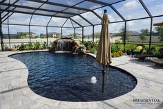 a pool with a waterfall and umbrellas in the middle is surrounded by glass walls