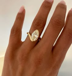 a woman's hand with a yellow diamond ring on top of her left hand