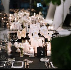 the table is set with candles, flowers and place settings for guests to sit at