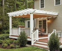 a white pergolan sitting on top of a wooden deck next to a house