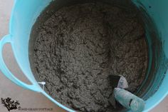 a blue bucket filled with dirt sitting on top of a cement floor