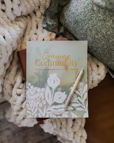 a book sitting on top of a blanket next to a cup and pen in front of it